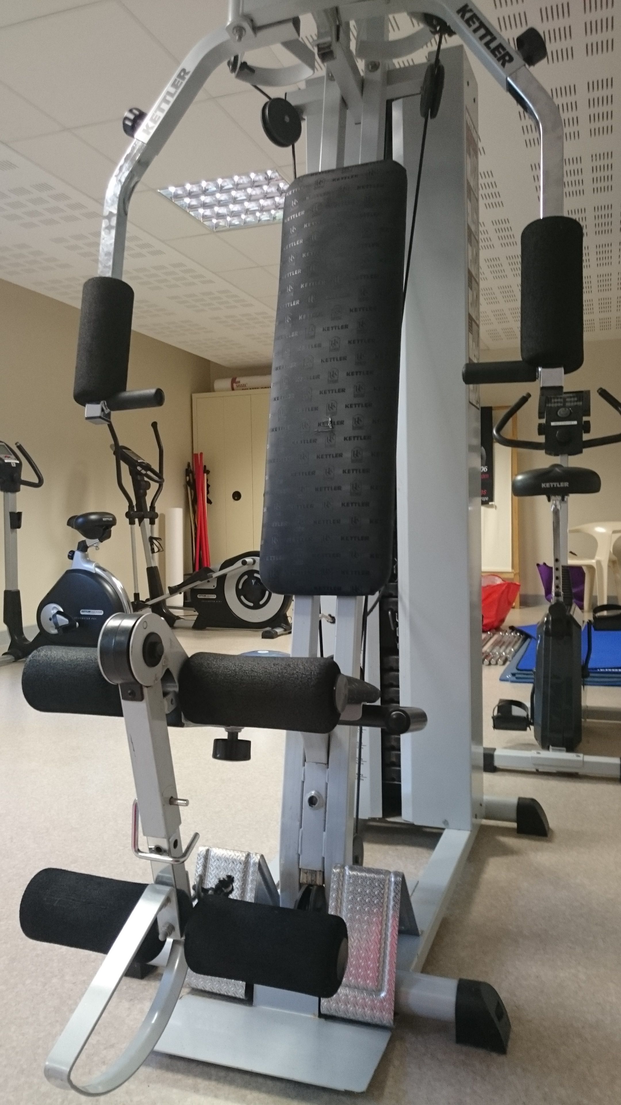A gym with a weight machine, exercise bikes, and a treadmill.