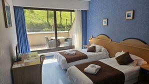 Une chambre d’hôtel avec deux lits, un bureau et une vue sur l’extérieur.