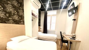 Een hotelkamer met een bed, een bureau, een stoel, een televisie en een raam.