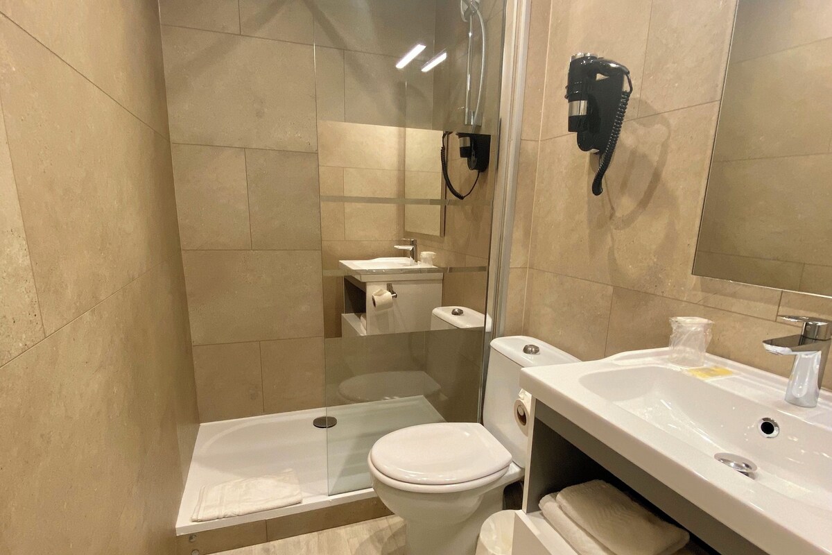 A modern bathroom with a shower, toilet, and sink.