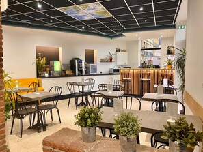 A modern cafe with a bar area, seating, and a ceiling with a geometric pattern.
