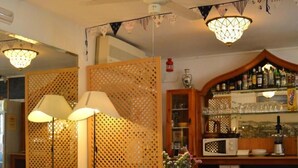 Un soggiorno accogliente con un divano, un tavolino in legno e un tavolo da pranzo. Si nota un pannello decorativo a parete e uno scaffale con diversi oggetti.