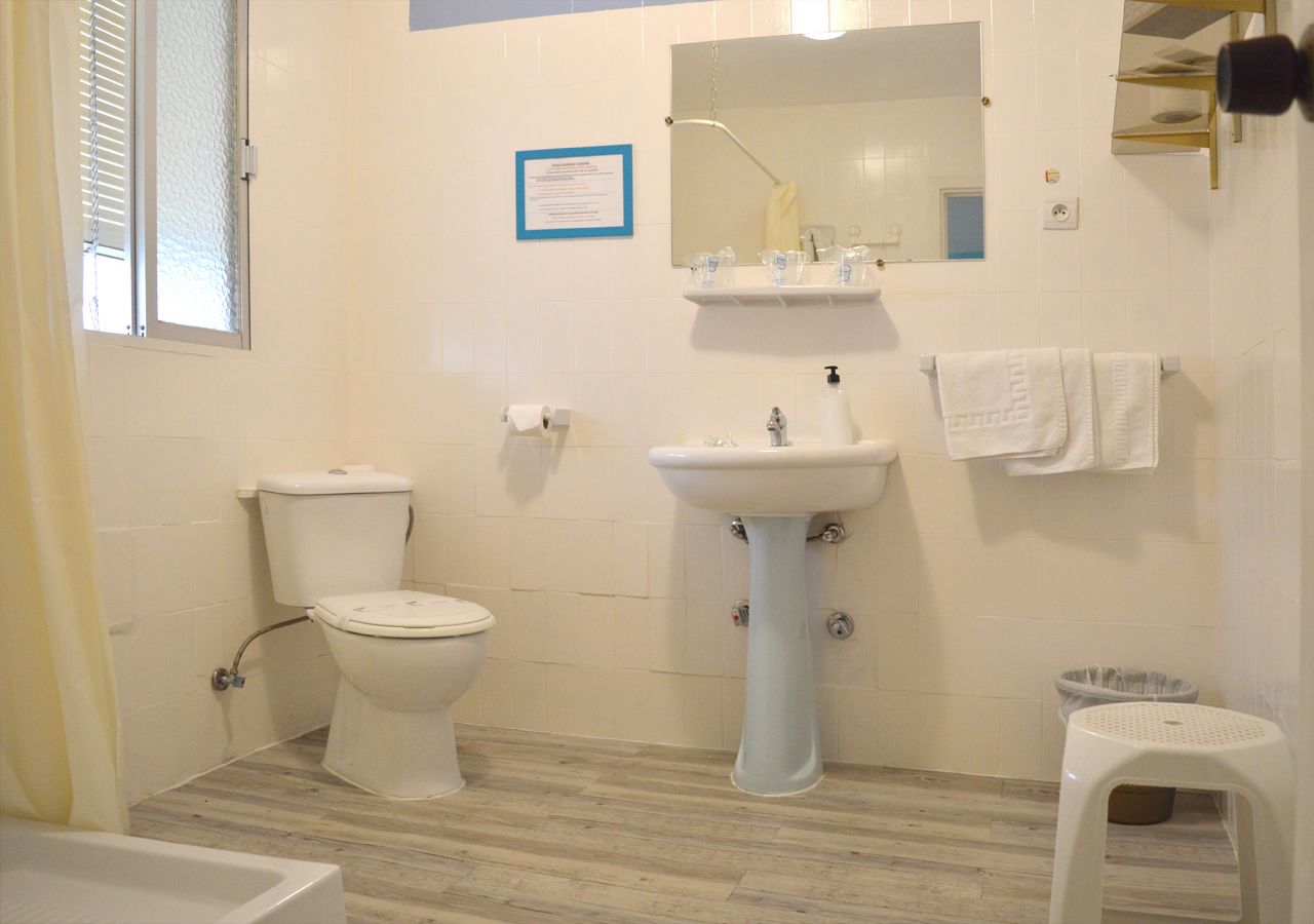 A bathroom with a toilet, sink, and mirror.