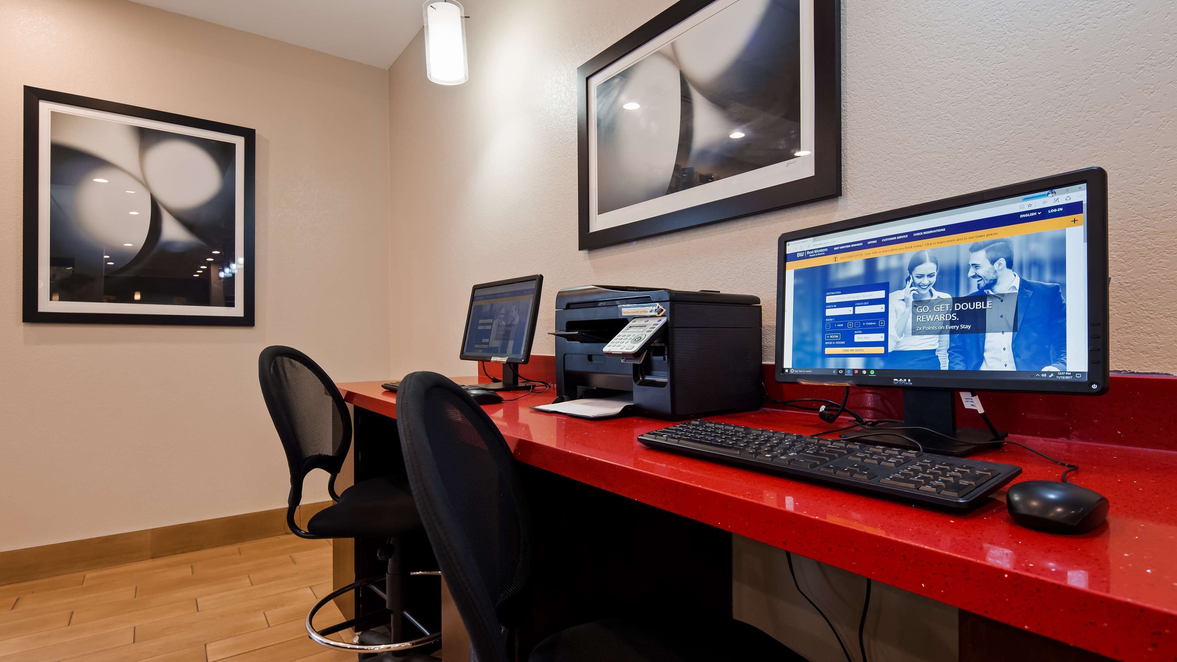 A hotel reception desk with a computer, printer, and chair.