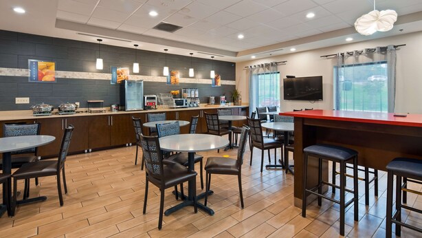 Um restaurante moderno com balcão, área de bar e diversas opções de assento, incluindo mesas redondas e banquetas.