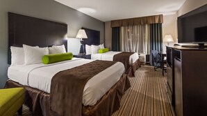 Quarto de hotel com duas camas, uma escrivaninha, uma cadeira, uma televisão e uma janela com cortinas.