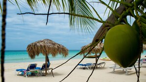 Una playa con sillas de descanso y una sombrilla de paja.
