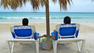 En la playa, playa de arena blanca, camastros y sombrillas