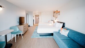 Una habitación de hotel moderna con una cama, un sofá, un escritorio y una silla.