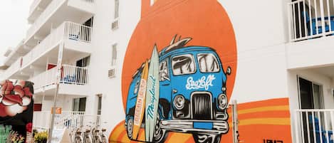 Un bâtiment orné d’une fresque représentant une voiture ancienne et d’une enseigne sur laquelle on peut lire « SeaCoast ».
