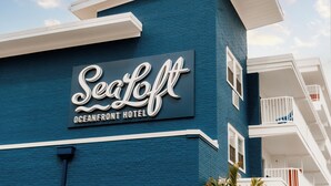 Exterior del Hotel SeaLoft Oceanfront, con un letrero llamativo y un balcón con barandillas blancas.