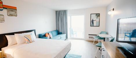 A modern hotel room with a large bed, a sofa, a desk, and a television.