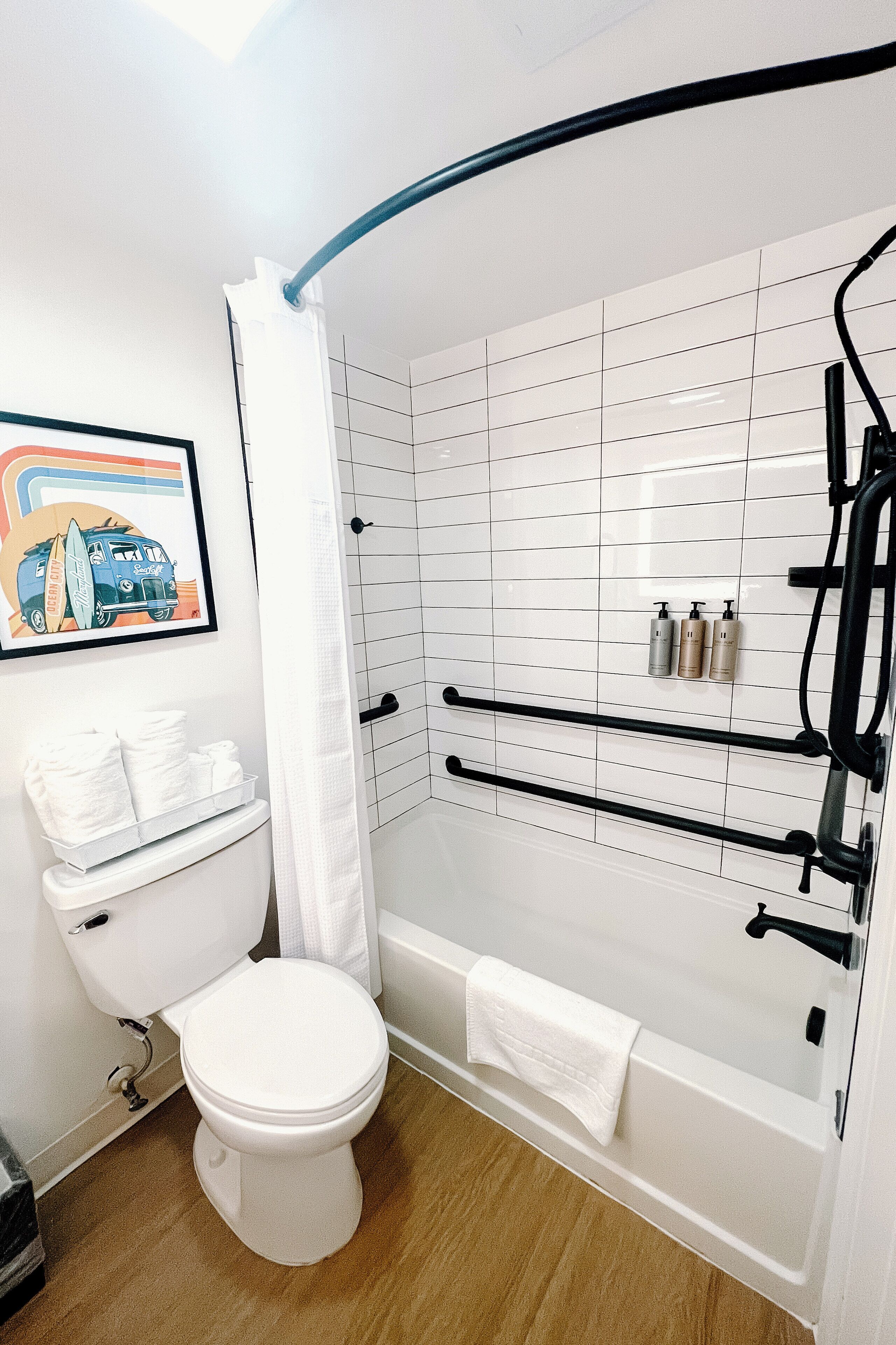 A bathroom with a white toilet, a bathtub, a shower with a curved door, and a towel rack.