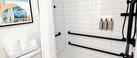 A bathroom with a white toilet, a bathtub, a shower with a curved door, and a towel rack.