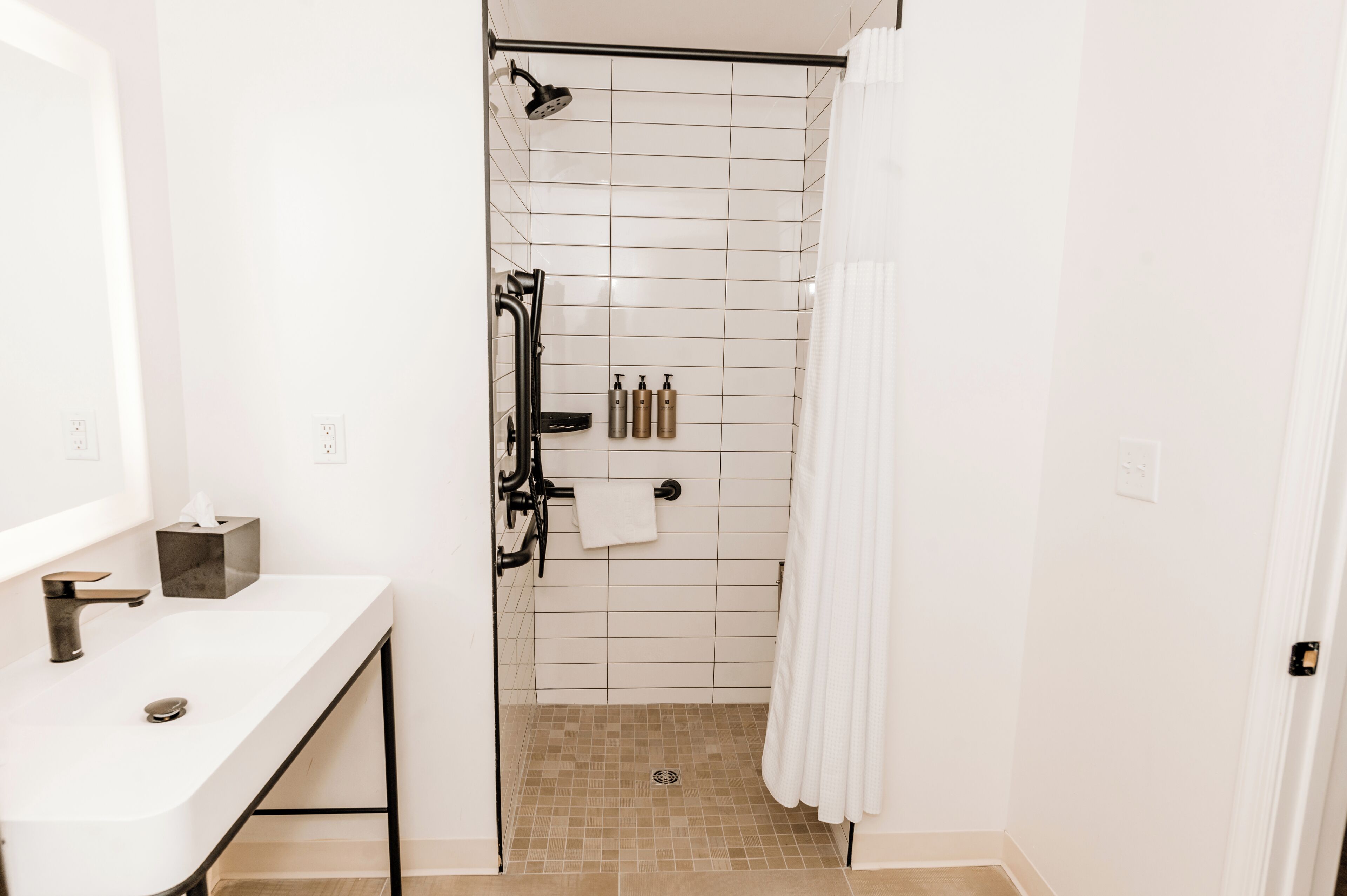 Un baño moderno con lavamanos blanco, cabina de ducha de vidrio y perchero.