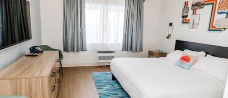 A modern hotel room with a large bed, a desk, and a TV.