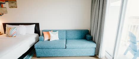 Una camera d'albergo con un letto, un divano blu e un'ampia finestra.