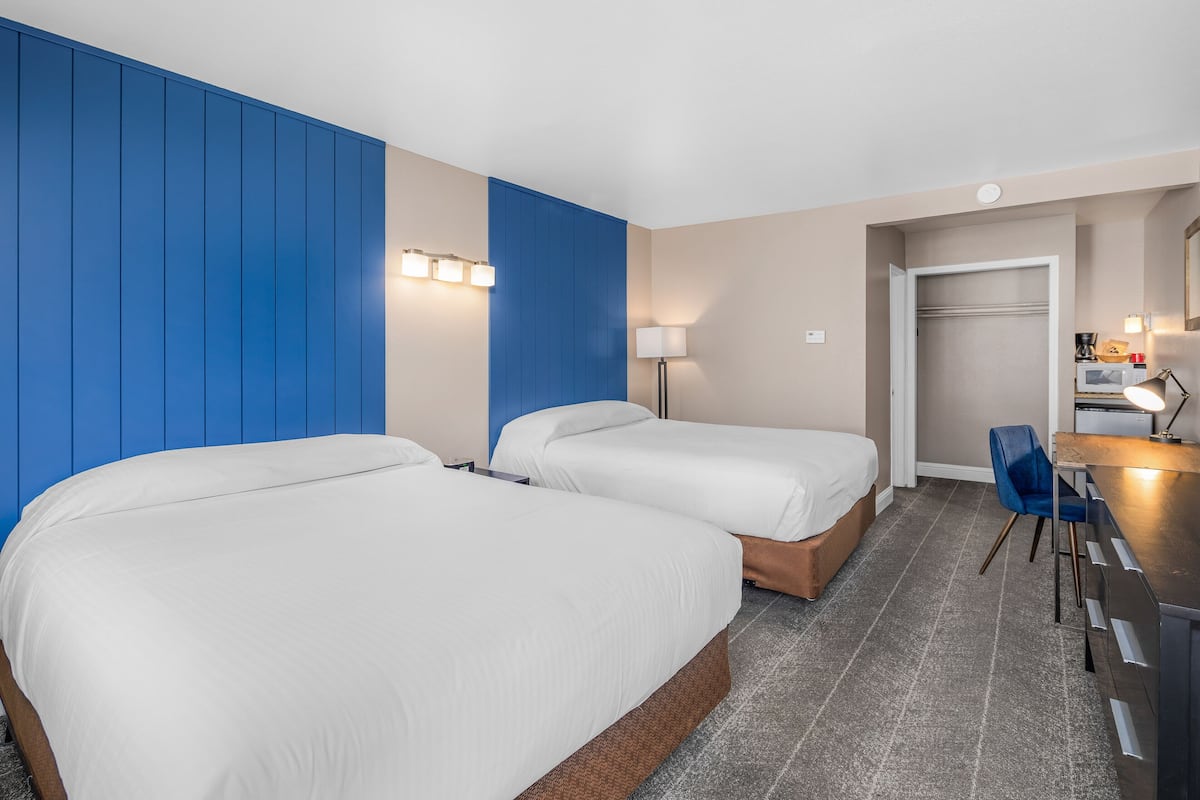 Une chambre d’hôtel avec deux lits, un bureau et une chaise.