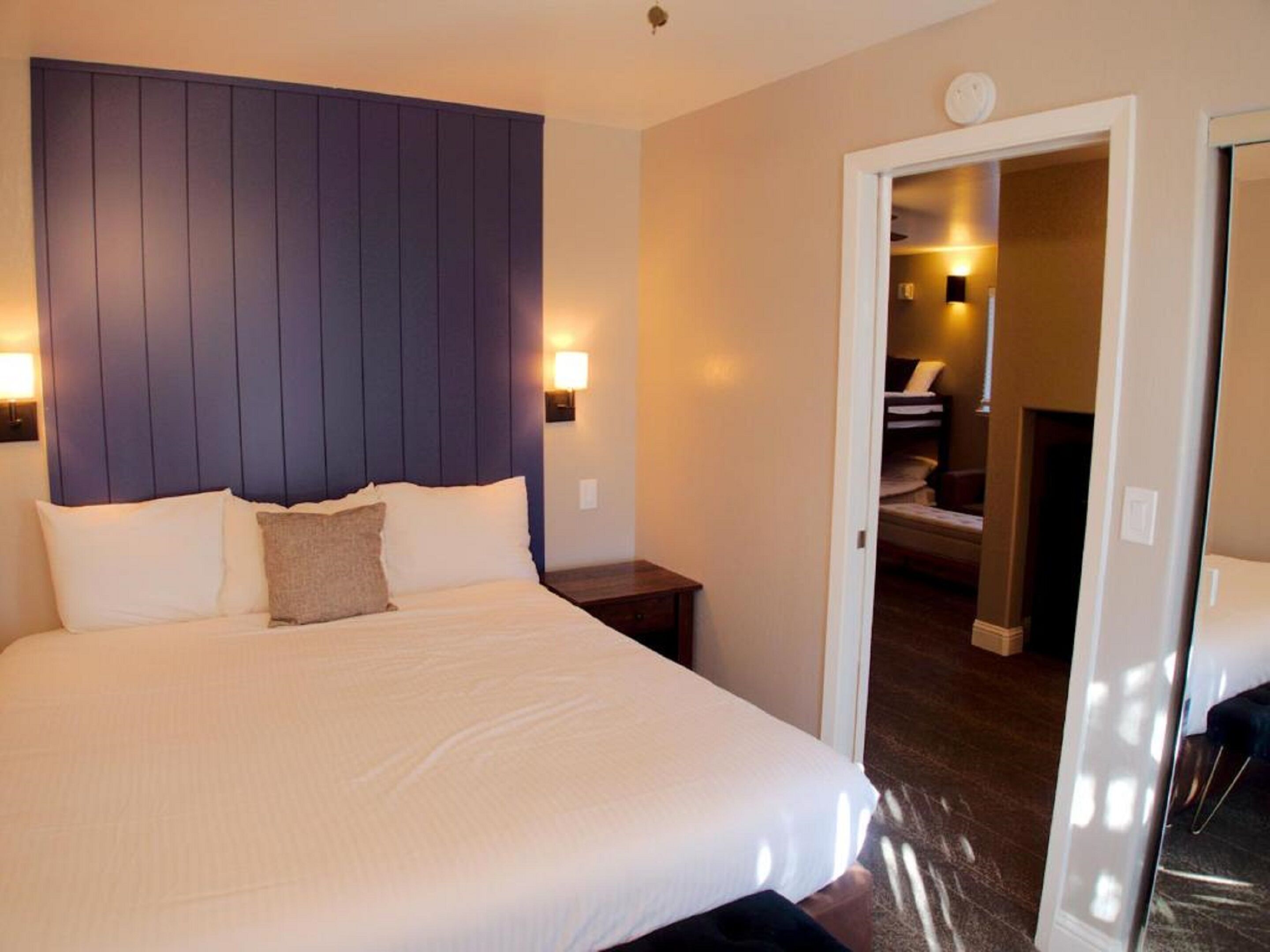 A neatly made bed with a headboard, bedside tables, and a lamp.