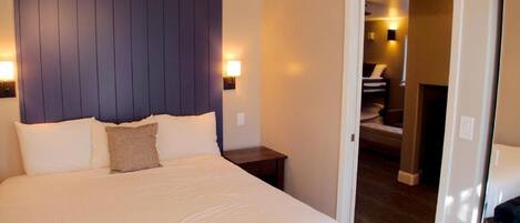 A neatly made bed with a headboard, bedside tables, and a lamp.