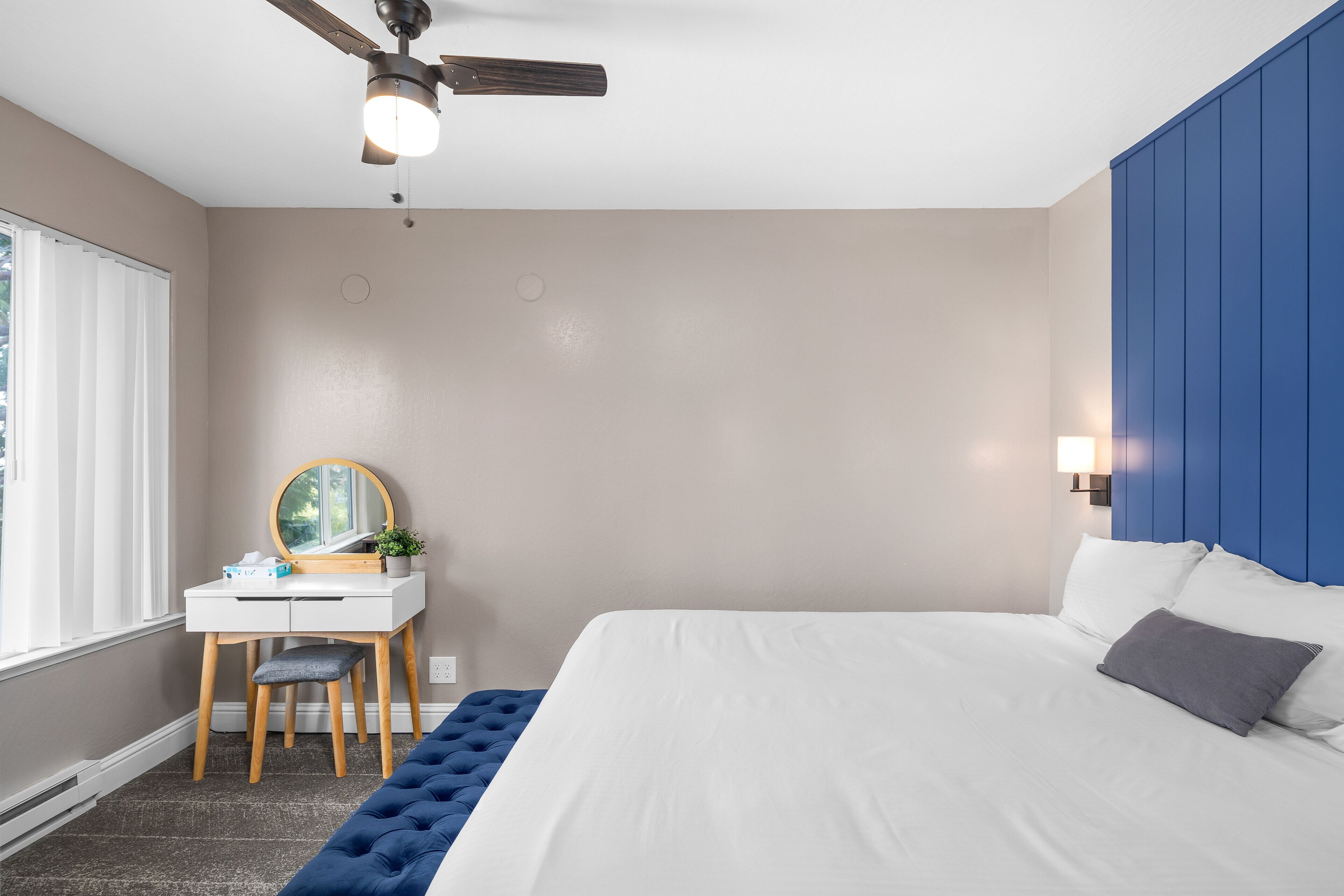 Une chambre à coucher avec un lit, un bureau et une chaise, un ventilateur de plafond et une fenêtre.