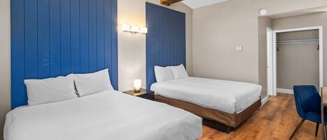 Habitación de hotel con dos camas, suelo de madera y una pared azul de detalles.