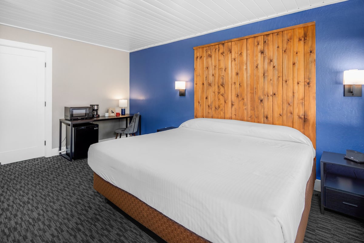 Une chambre d’hôtel avec un grand lit, un bureau équipé d’un four à micro-ondes, d’une machine à café et d’un petit réfrigérateur.