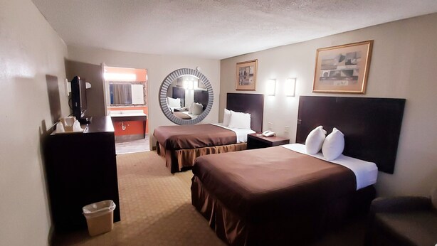 A hotel room with two beds, a desk, a chair, a mirror, and a bathroom visible through an open door. - Executive Inn (Pensacola)