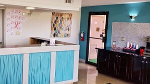 A reception area with a counter, a clock, informational posters, and a fire extinguisher. - Executive Inn (Pensacola)