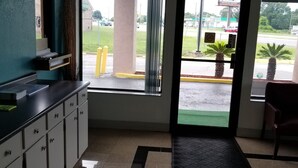 A reception area with a counter, a reception desk, an exit sign, and a view of the parking lot. - Executive Inn (Pensacola)