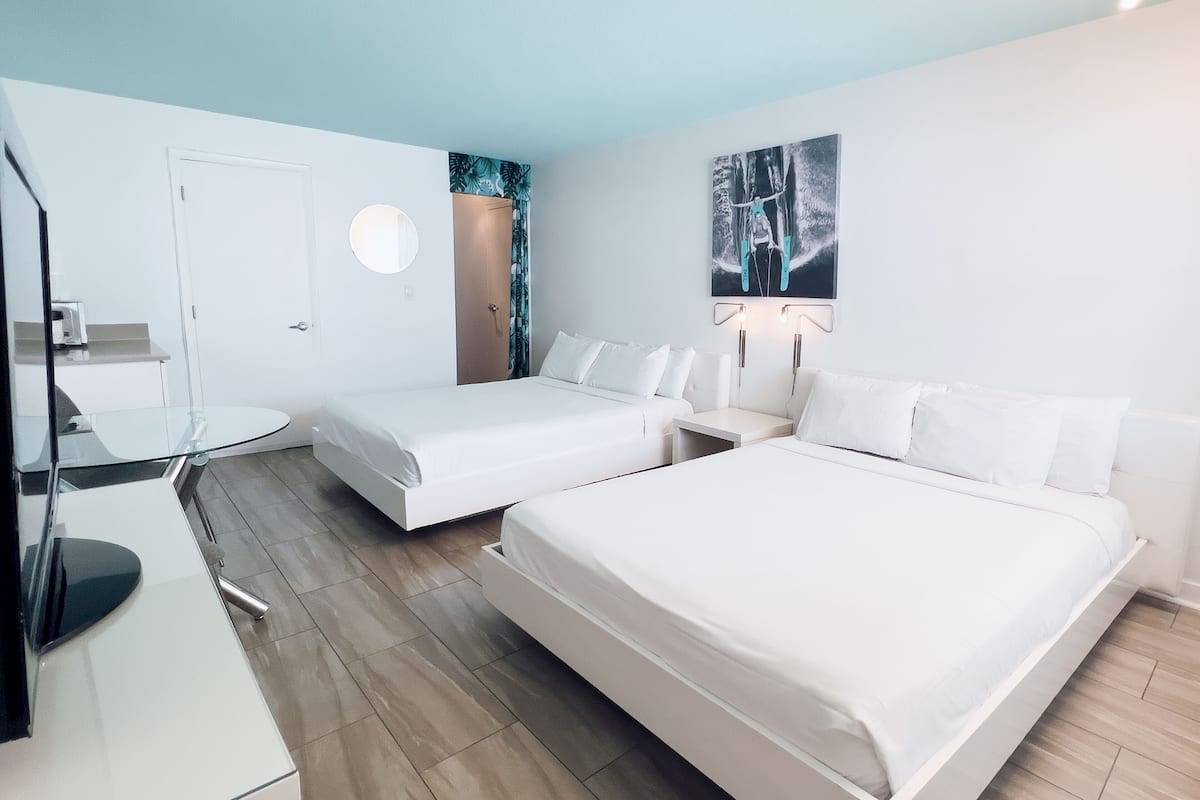 Une chambre d’hôtel avec deux lits, un bureau et un miroir.