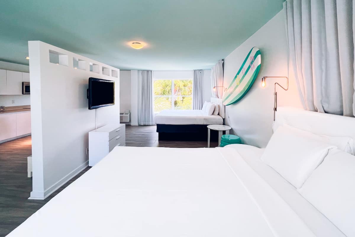 Une chambre d’hôtel moderne dotée d’un grand lit, d’une télévision à écran plat, d’une petite table et offrant une vue sur l’extérieur.