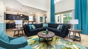 A spacious living area with a sectional sofa, two side tables, and a coffee table. A kitchen is visible in the background. - Paradise Palms Resort by Global Resort Homes (Kissimmee)