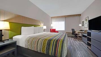 Ein Hotelzimmer mit Bett, Schreibtisch, Stuhl, Fernseher und Fenster.