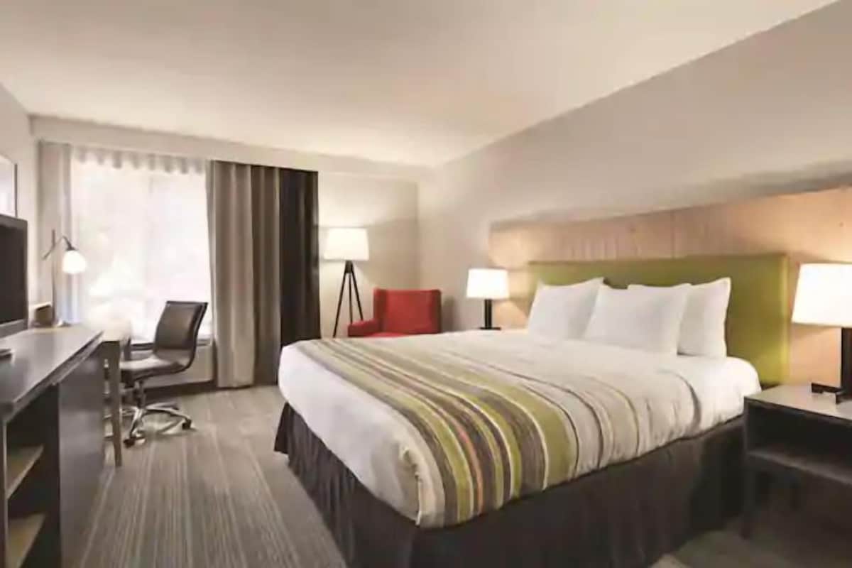 A hotel room with a bed, a desk, a chair, and two bedside lamps.