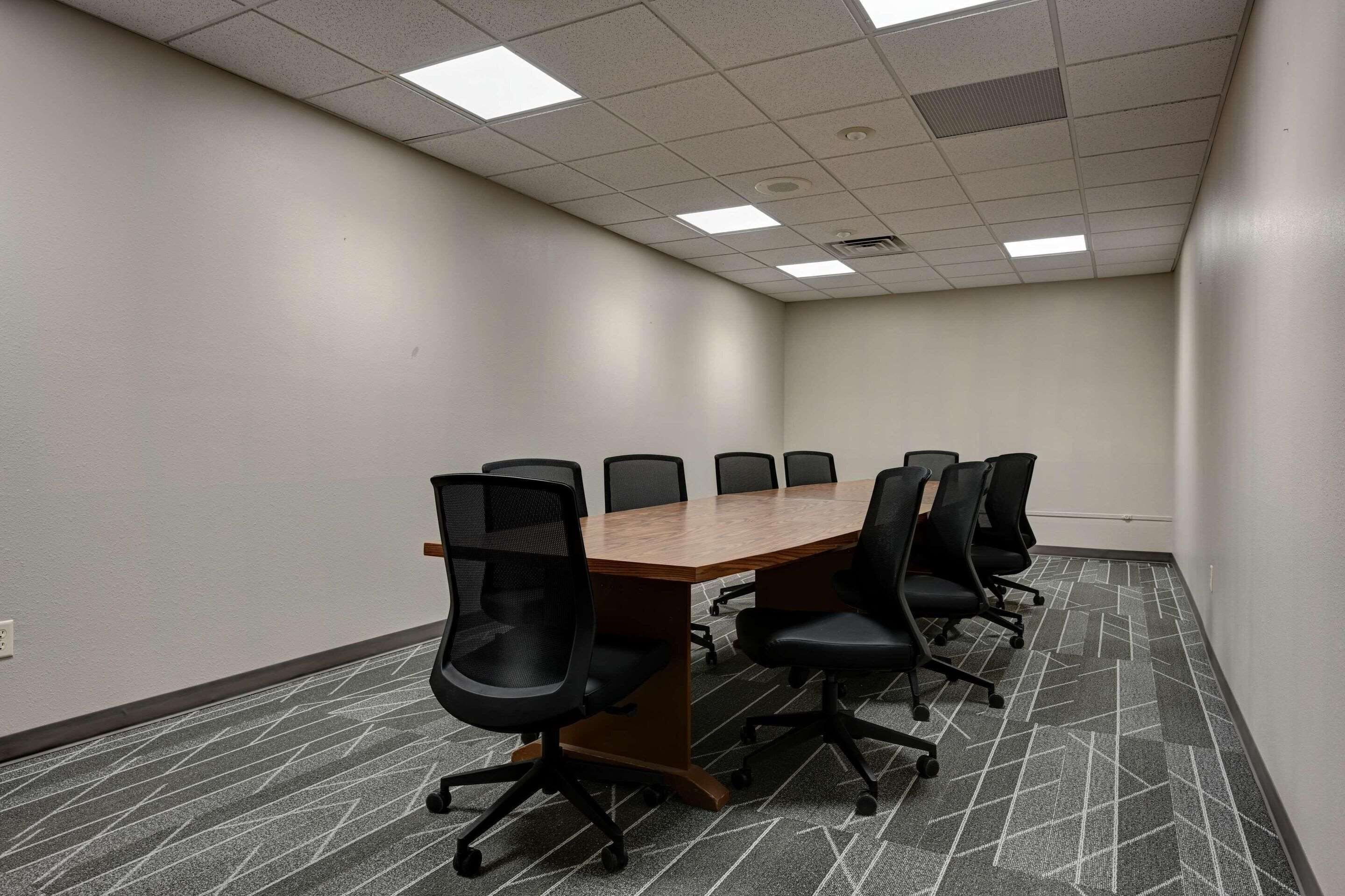 A conference room with a long table and six chairs.