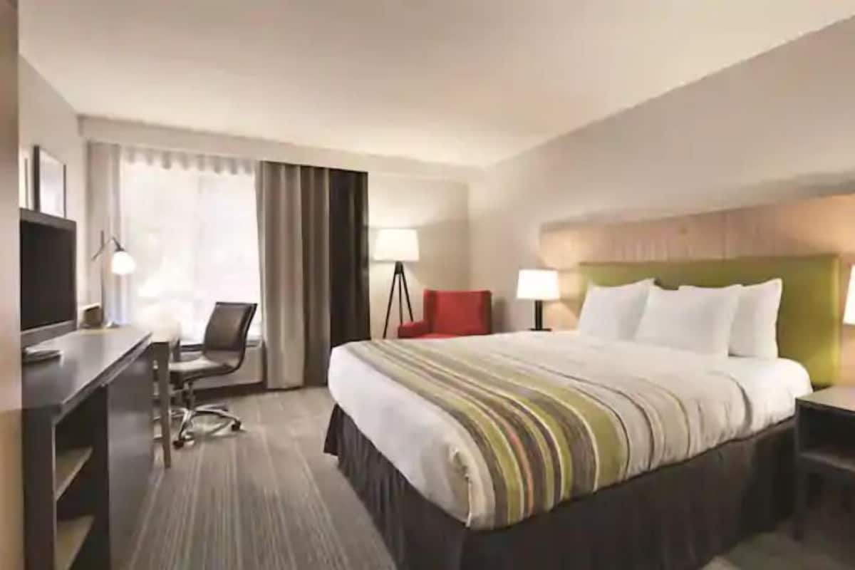 A hotel room with a bed, a desk, a chair, and two bedside lamps.