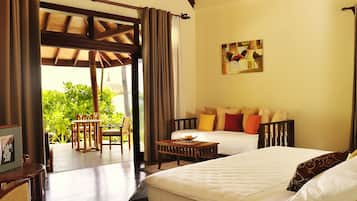 A hotel room with two beds, a wooden ceiling, a dining area with a table and chairs, and a view of greenery outside.