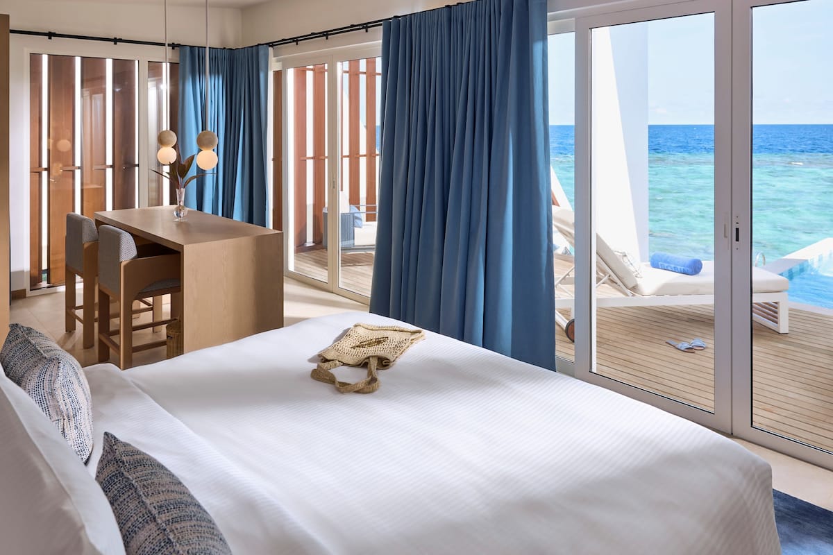 Une chambre d’hôtel avec un lit, un bureau et une vue sur l’océan.