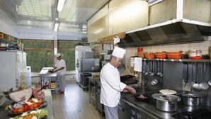 A commercial kitchen with stainless steel appliances, chefs preparing food, and various cooking utensils. - Le Chamois (Molines-en-Queyras)