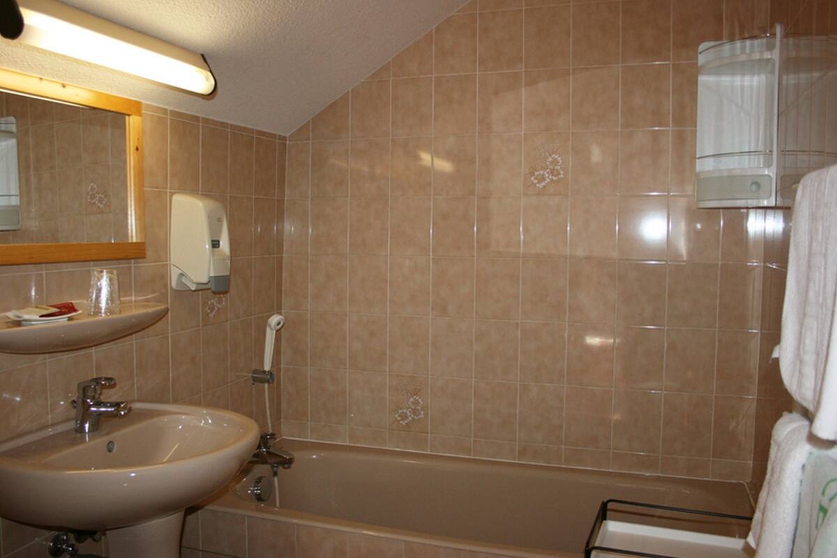 A bathroom with a sink, mirror, and bathtub.