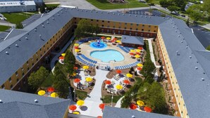 Un hotel con piscina central rodeada de sombrillas y tumbonas.