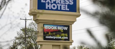 A sign for Cedar Point's Express Hotel with a 'BOOK NOW' screen below.