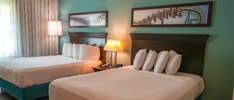 A hotel room with two beds, a nightstand with a lamp, and two framed pictures on the wall.
