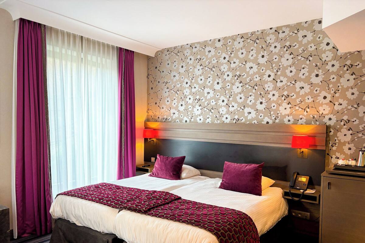 Una habitación de hotel con una cama grande, dos mesitas de noche, un escritorio y un armario.