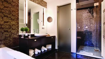Une salle de bain moderne avec un grand miroir, une baignoire et une douche séparée par une paroi de verre.