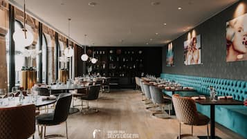 Un restaurant moderne avec des planchers en bois, des sièges noirs et turquoise, et des luminaires suspendus.