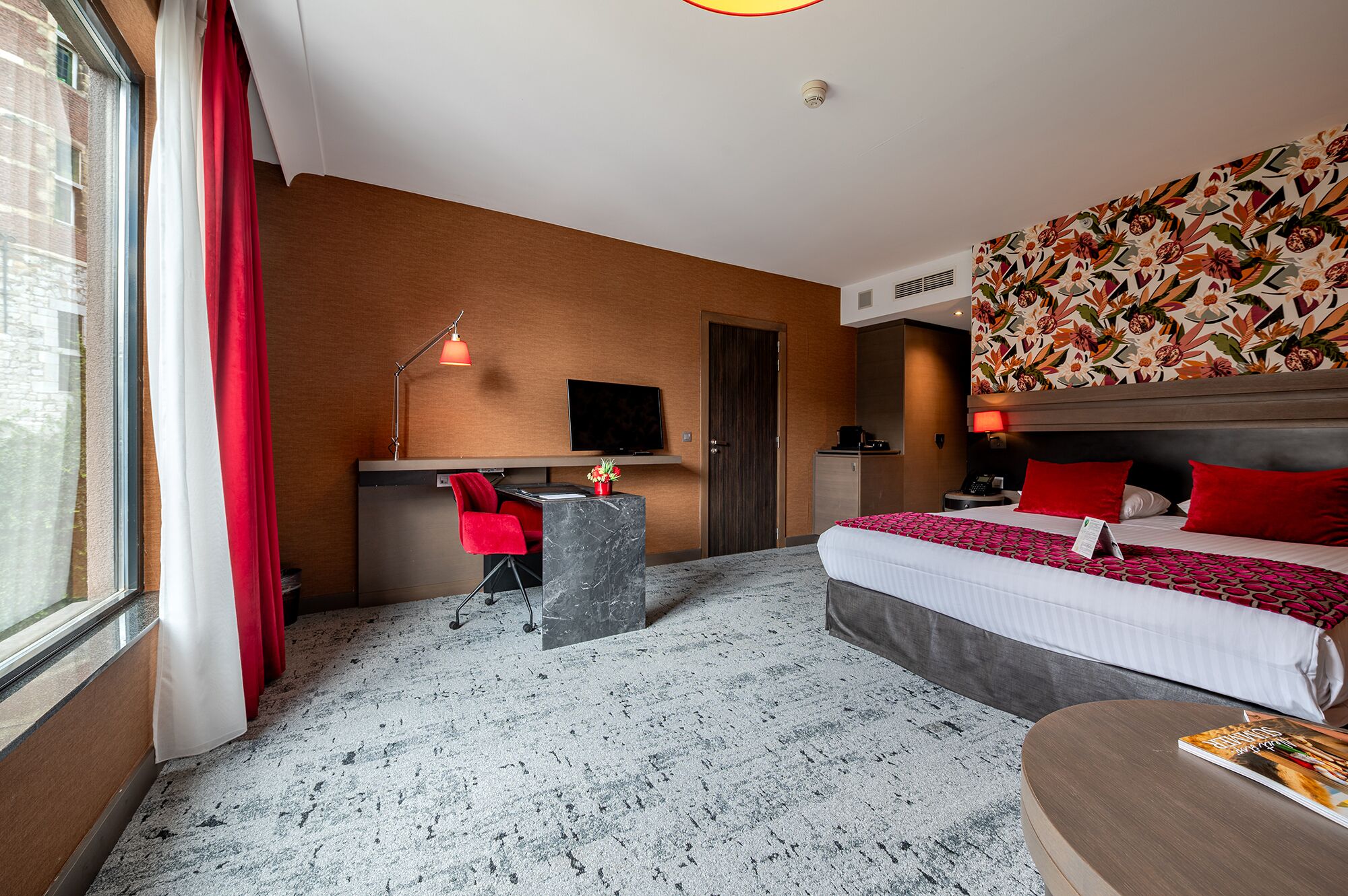 Habitación de hotel con cama, escritorio, silla y televisor.