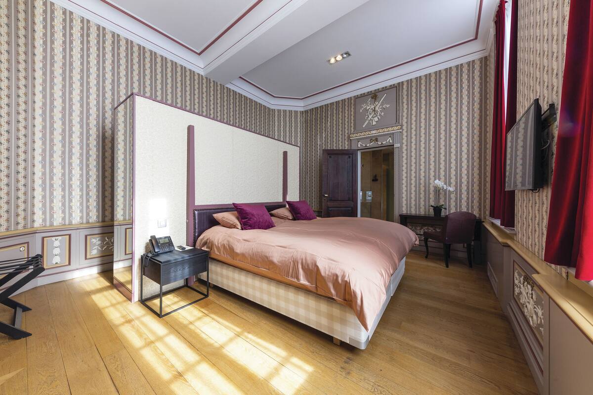Un dormitorio con una cama grande, un escritorio, una silla y un armario.