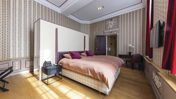A bedroom with a large bed, a desk, a chair, and a wardrobe.
